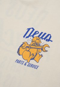 Hvid T-shirt med en tegneserie-egern i gul, der holder en skruenøgle, med "Deus" i blå ovenfor og "PARTS & SERVICE" nedenfor i blå tekst.