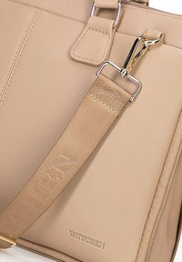 Beige leren handtas met een gestructureerd oppervlak, gouden hardware en een gevlochten band met de merknaam "WITTCHEN" in reliëfletters.