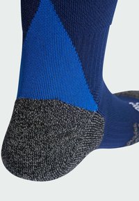 Calcetín atlético azul marino y azul con textura acanalada, talón y puntera grises reforzados, y detalle de logo integrado en el lateral.