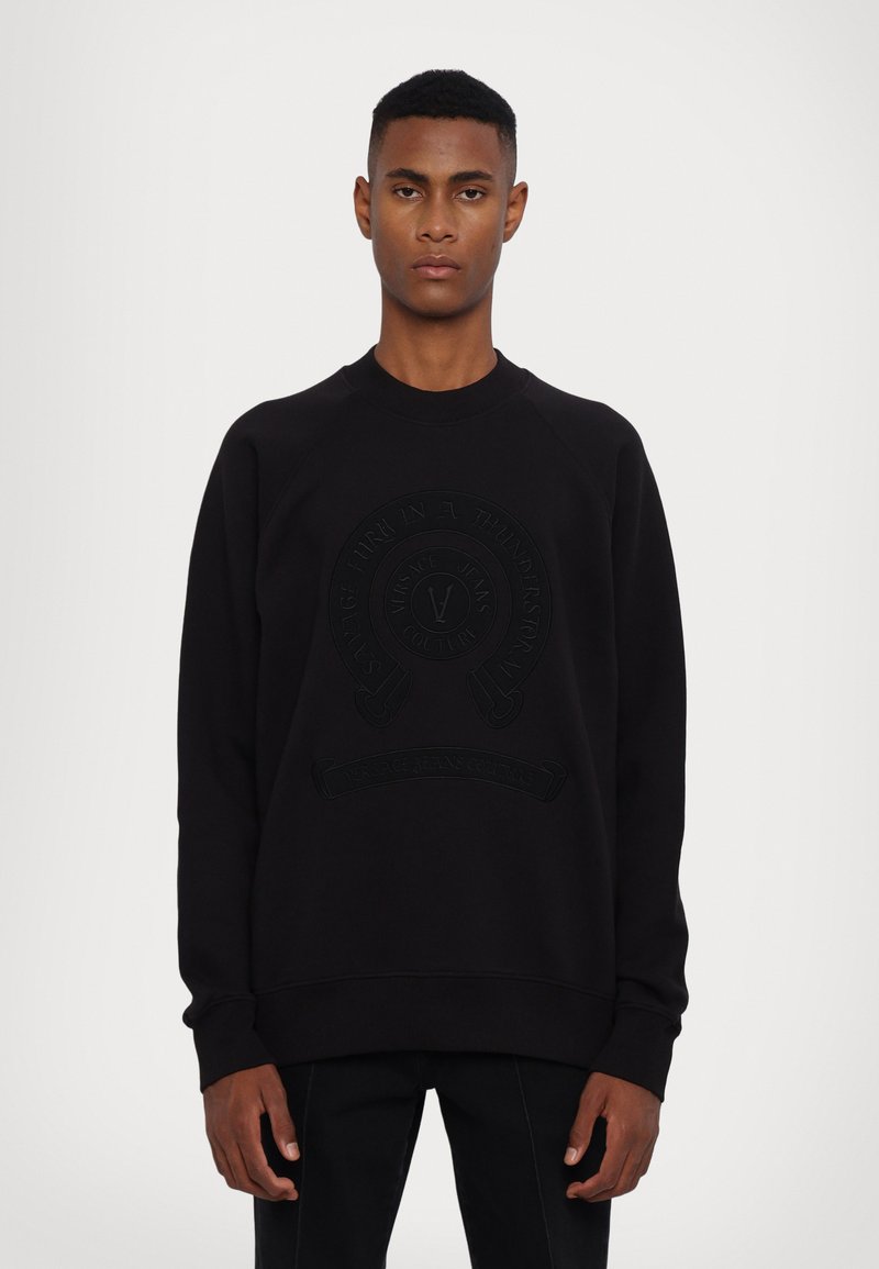 Sort sweatshirt med rund hals og ribbede manchetter, med et prægget logo i midten. Fremstillet af blødt stof med en glat tekstur.