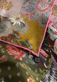 Zijden sjaal met levendige bloemen- en paisleypatronen in roze, groen, geel en zwart, met een opvallende roze rand en logo-label.