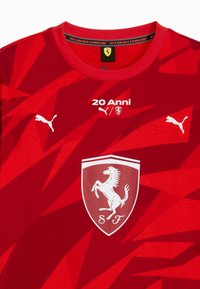 Rode T-shirt met een geometrisch patroon, zwart-witte Puma-logo's en een groot wit Ferrari-paardenembleem met de tekst "20 Anni".