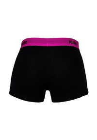 Schwarze Boxershorts für Männer mit einem breiten rosa Bund, der am Rücken mittig die Aufschrift "HUGO" in schwarzen Buchstaben trägt.