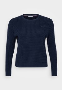 Marineblå strikket genser med lange ermer, rund hals og strukturmønster over stoffet. Lite logo på brystet.