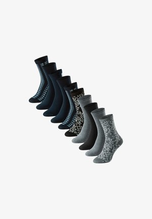 Nove paia di calze a lunghezza fonda in nero, grigio e blu navy con motivi floreali e geometrici disposti in una linea diagonale.