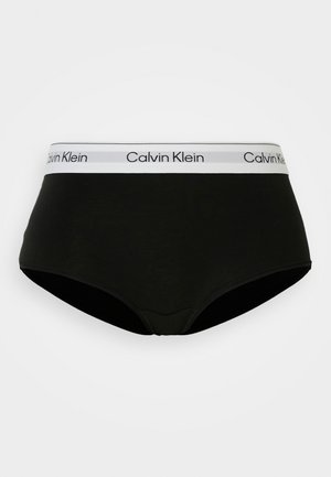Culotte noire en coton avec une large ceinture élastique blanche portant le logo "Calvin Klein". Texture lisse, coupe mi-haute, sans motifs supplémentaires.