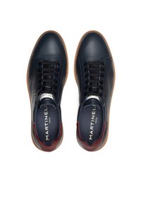 Zapatillas de piel azul marino con suela de goma marrón, con cordones negros y detalles burdeos en el talón y la lengüeta. Logo de la marca visible en el interior.
