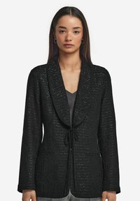 Svart texturerad kavaj med knytstängning, notch-lapel och två framfickor. Tyget har ett subtilt mönster och en strukturerad passform.