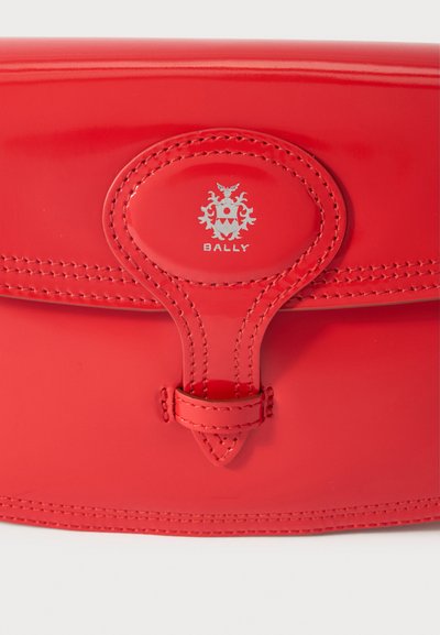 Red patent leather bag featuring a central silver logo, stitched accents, and a distinctive clasp detail. Intricate texture enhances design.