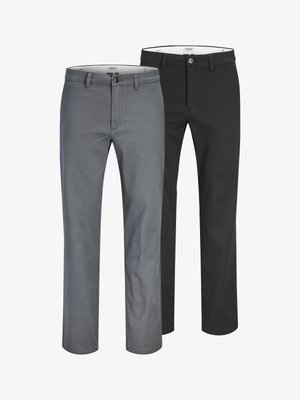 Kaks paari meeste kitsas lõikega pükse, üks hall ja üks must, eksponeeritud kõrvuti valgel taustal.