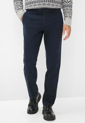 Marineblaue Hose aus gewebtem Stoff, mit Seitentaschen und lockerer Passform sowie glatter Textur; getragen mit schwarzen Schuhen.