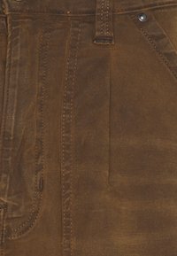 Bruna kordfløyelsbyxor med synlig ribbtextur, med orange sömmar, traditionell femficksdesign och metallknappstängning.