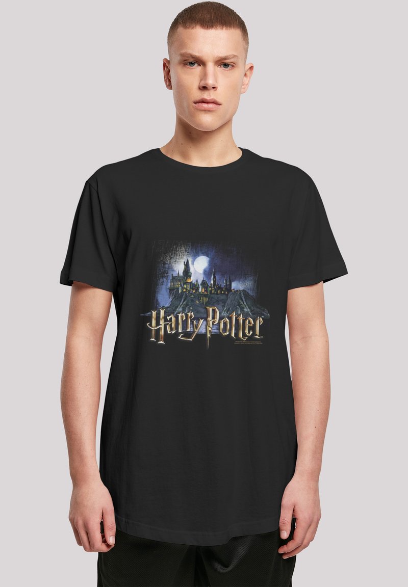 Black cotton t-shirt featuring a graphic of Hogwarts with a moon, and the text "Harry Potter" in metallic gold font. Short sleeves, relaxed fit.