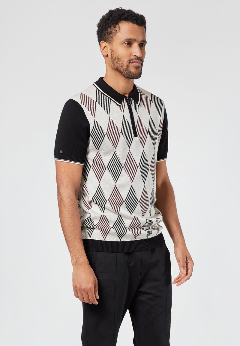 Lyhythihainen polo-paita mustalla kauluksella, jossa on teksturoitu timanttikuvio vaaleassa beigeessä, viininpunaisessa ja mustassa. Ribbaus helman ja hihansuiden ympärillä.