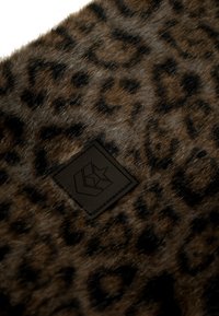 Leopardprint nepbont stof met een gladde textuur en een zwart leren label met reliëflogo in de hoek.