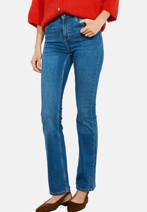 Niebieskie dżinsy z denimu o dopasowanym kroju, wysokim stanie i lekko rozszerzane u dołu. Charakteryzują się widocznym przeszyciem i gładką fakturą.