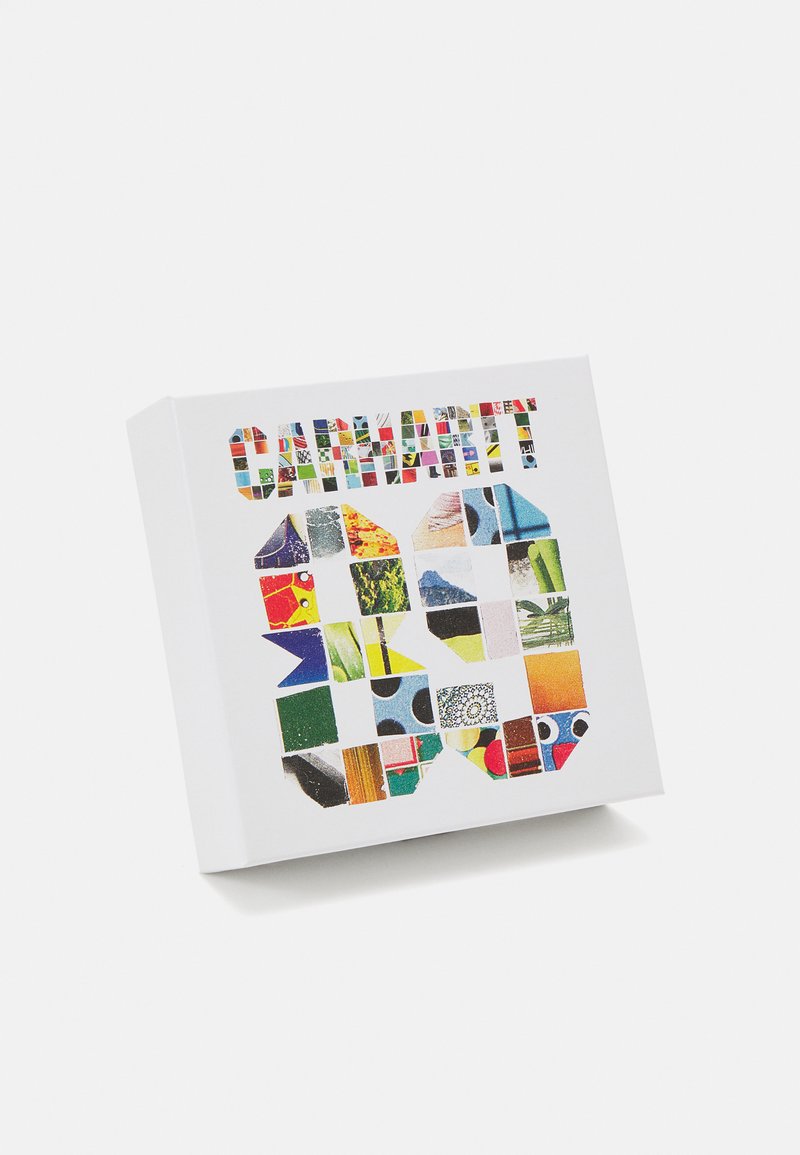 Hvid boks med et farverigt collage af mønstre og teksturer arrangeret i gitterformer, med ordet "KARNEVAL" præsenteret tydeligt.