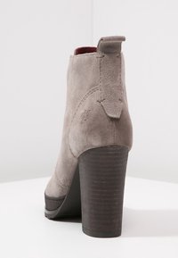Gray suede ankle boot with a high stacked heel, rounded toe, and a pull tab on the back. Features a textured heel for added grip.