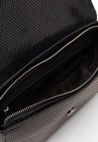 Borsa nera con motivo a pelle di serpente testurizzata. L'interno presenta una fodera in tessuto scuro e una chiusura con cerniera argentata per la suddivisione degli spazi.