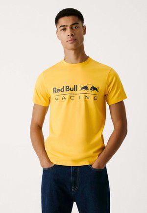 Gelbes Baumwoll-T-Shirt mit kurzen Ärmeln. Mit dem schwarzen "Red Bull Racing"-Grafikdesign auf der Brust. Einfarbig, lässige Passform.