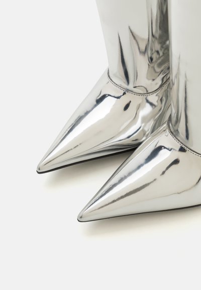 Metallic silver ankle boots with pointed toes, smooth texture, and a sleek design. Stitching detail visible at the ankle seam.