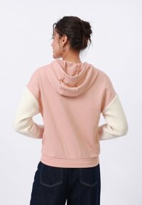 Mikina s kapucňou s pink telom a krémovými fleecovými rukávmi. Má voľný strih a kontrastný štruktúrovaný materiál. Ideálna na každodenné nosenie.