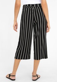 Zwart-witte gestreepte culottebroeken met een brede pijpdesign, elastische tailleband en lengte tot halverwege de kuit. Soepele stoftextuur.