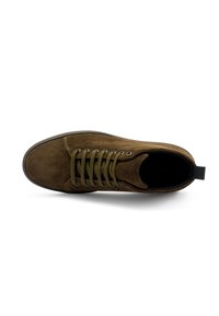 Zapato de ante marrón con cordones verde oliva, puntera redonda y forro negro. Cuenta con una suela de goma y un lazo en el tacón para ponérselo fácilmente.