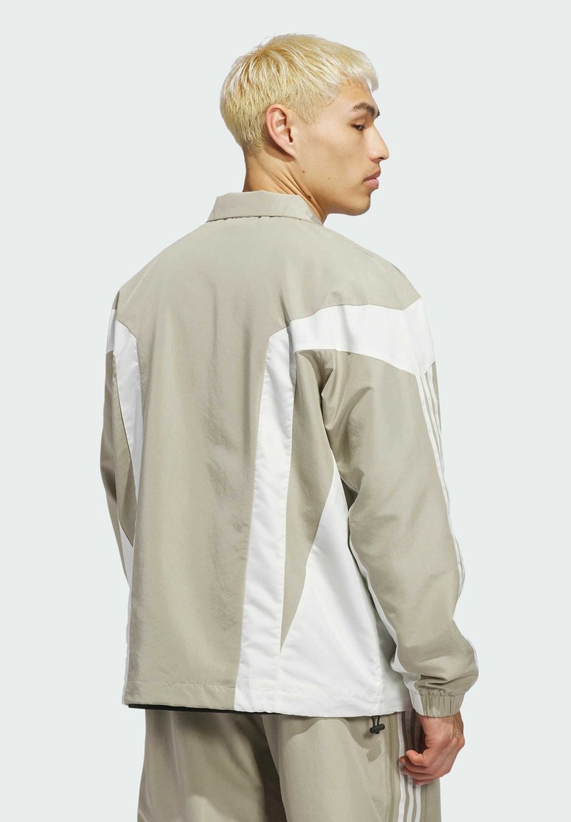 Lightweight, beige jacket with white accents, featuring a relaxed fit, elastic cuffs, and a stand-up collar, shown from the back.
