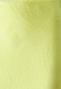 Tissu jaune clair avec une texture lisse et légèrement froissée. Design simple sans motifs ni ornements. Ourlet cousu.