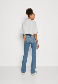 Gray cropped t-shirt with short sleeves paired with high-waisted blue jeans featuring flared legs and back pocket detailing.