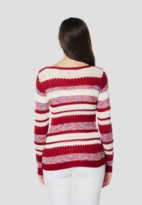 Gebreide trui met rode, witte en meerkleurige strepen, met opengewerkte accenten en een ronde halslijn. Lange mouwen en een getailleerd ontwerp.