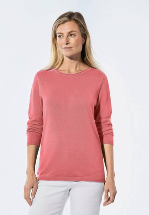 Korallfarbener Strickpullover mit Dreiviertelärmeln, runder Halslinie und gerippten Bündchen, kombiniert mit hellen Jeans. Glatte Textur und lässige Passform.