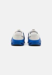 Baskets de sport bleues et blanches avec une tige en maille, texture lisse, talon rembourré et détails sur les côtés et la semelle.