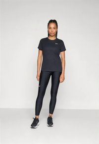 Camiseta deportiva negra de manga corta, combinada con leggings negros brillantes. Ambos artículos llevan el logo de Under Armour.