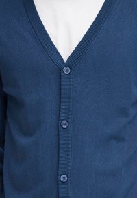 Cardigan lavorato a maglia blu navy con scollo a V, caratterizzato da un bordo a coste e cinque bottoni blu sul davanti. Texture morbida e design aderente.