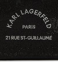 Schwarzer texturierter Stoff mit silbernen Nieten und Branding: "KARL LAGERFELD PARIS" und "21 RUE ST-GUILLAUME" in gekurvtem und geradem Text.