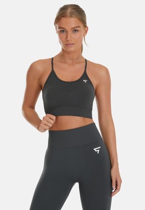 Dark gray sports bra with thin straps and a logo. High-waisted dark gray leggings feature a seamless design and a logo on the side.