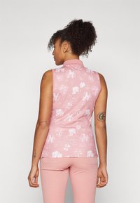 Sleeveless polo shirt in soft pink with white floral patterns, featuring a collar and a fitted design. Material appears smooth and stretchy.