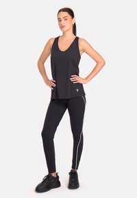 Musthave mustriba ilmanvarrukatega must sportlik särk, mille juurde on sobitatud mustad jalgpüksid, millel on valged küljelintid. Materjal tundub veniv; särk on lõdva lõikega.