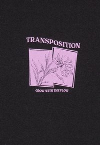 Tela negra con un gráfico rosa que presenta un dibujo lineal de una flor, el texto dice "TRANSPOSICIÓN" y "CRECE CON EL FLUJO."