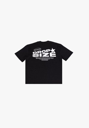 T-shirt en coton noir avec un texte blanc audacieux au dos, incluant "DROP SIZE" et d'autres phrases. Manches courtes et col rond.