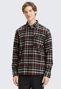 Czarna, czerwona i biała koszula w kratę z kołnierzykiem na guziki i pojedynczą kieszenią na piersi. Wykonana z tkaniny o miękkiej fakturze, z długimi rękawami.
