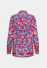 Röd blouse med lång ärm som har ett blomstertryck i blått och vitt. Noterbara ränder längs den nedre fållen. Knäppt bakre krage.