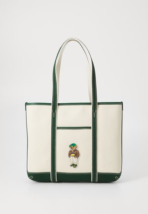 Sac fourre-tout en toile avec des couleurs vertes et crème, mettant en avant des coutures vertes et un ours brodé portant une veste et une casquette sur le devant.