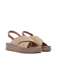 Brown woven sandals with a platform sole, featuring an open toe, adjustable buckle straps, and a textured design on the vamp.