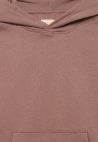 Φούτερ με κουκούλα σε απαλό ροζ χρώμα, κατασκευασμένο από απαλό ύφασμα. Διαθέτει μπροστινή τσέπη τύπου καγκουρό και κλασικό σχεδιασμό με απλό λαιμόκοψη.