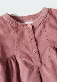 R�ůžové kordové šaty s kulatým výstřihem, které mají přední záhyby a čtyři sladěné knoflíky, se vyznačují měkkou texturou a strukturovaným tvarem.