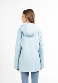 Jachetă impermeabilă de culoare albastru deschis, cu glugă, având o croială dreaptă și mâneci lungi. Textură netedă cu buzunare laterale și închideri cu capse.