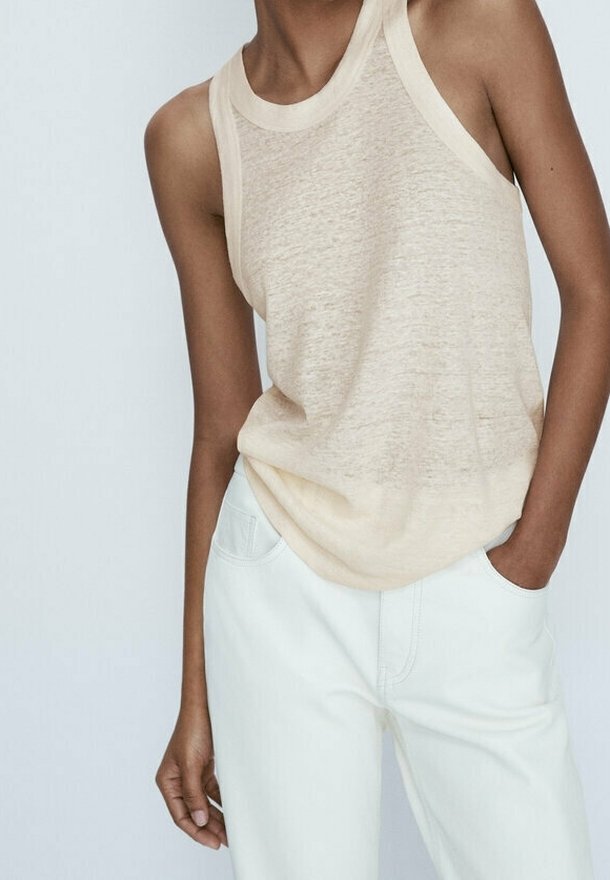 Beige mouwloze tanktop gemaakt van lichtgewicht stof met een gestructureerde afwerking, gecombineerd met lichte broek met voorzakken.